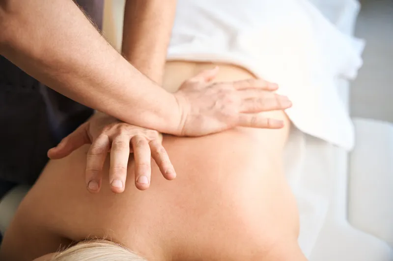 Therapist applying manual pressure to a patient's upper back during a Tuina massage session to relieve muscle tension and support relaxation.