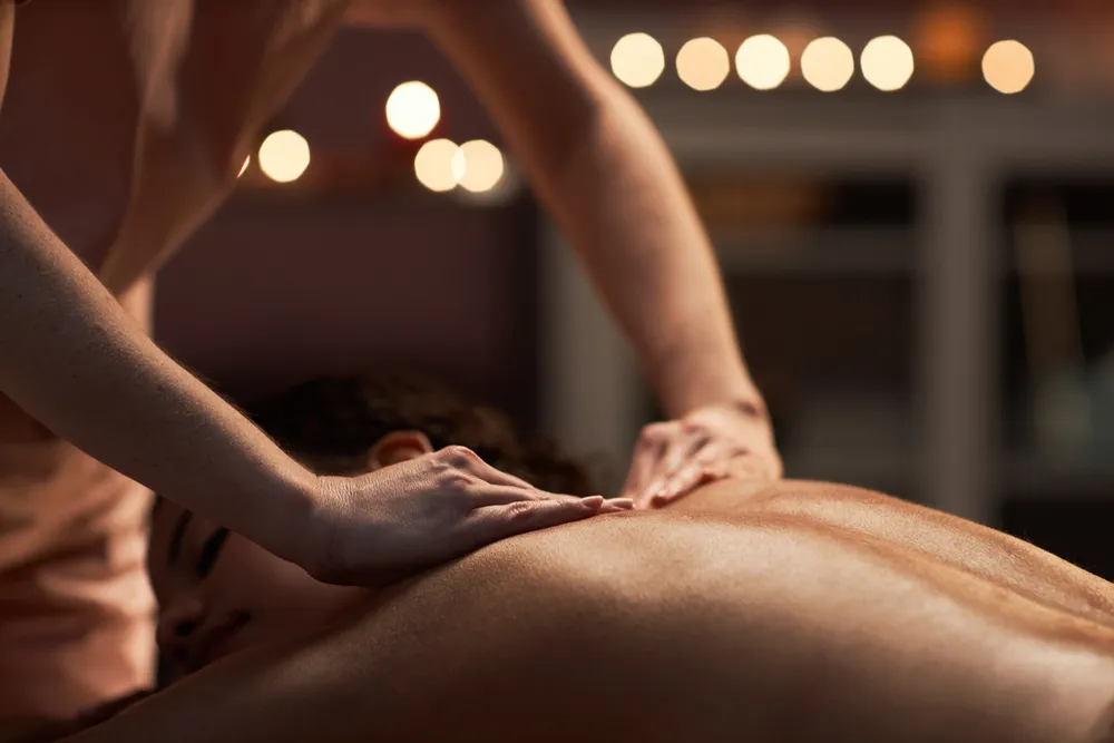 Therapist performing Tuina massage on a patient's upper back using manual pressure techniques to promote relaxation and relieve muscle tension.