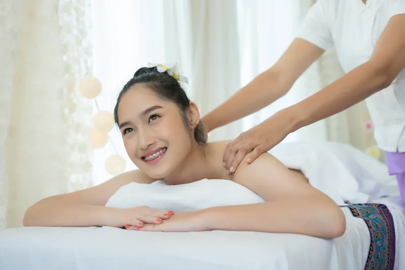 Woman receiving a Tuina massage on her neck and shoulders to help relieve muscle tension and promote relaxation.
