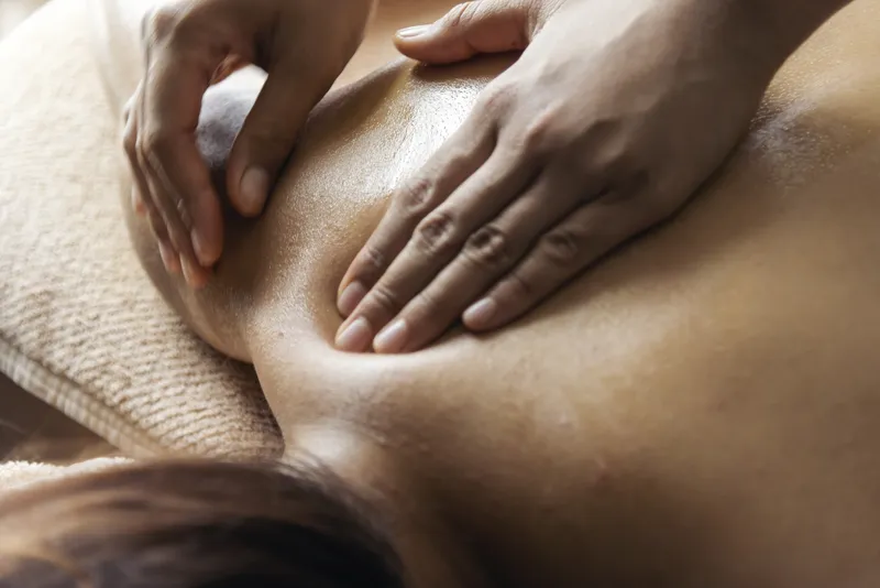 an image showing a TCM practitioner's hands pressing on meridian points to address shoulder pain on the woman's patient