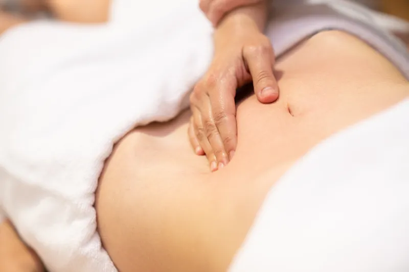 a close-up shot of a TCM practitioner's hand checking on the woman's meridian points to find the root cause of infertility